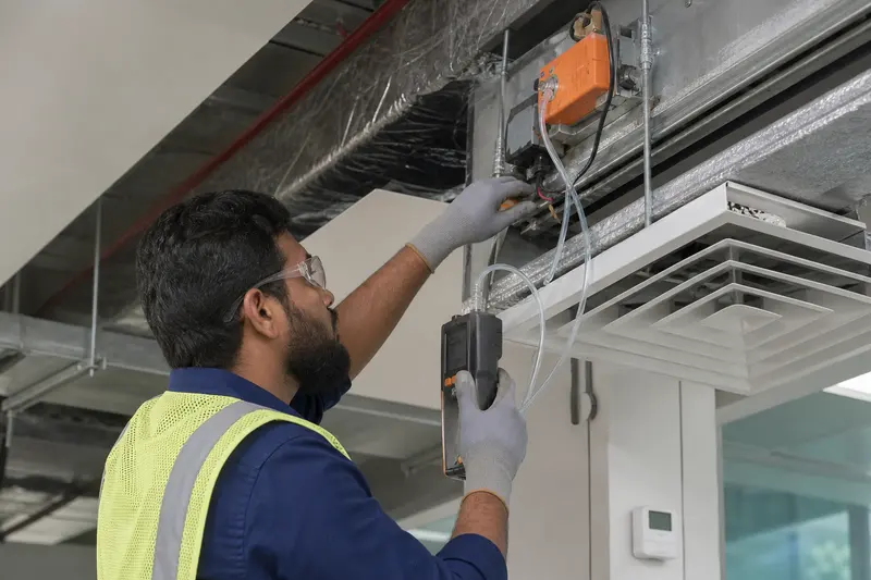 Technician measures differential pressure while checking an office air-control actuator.