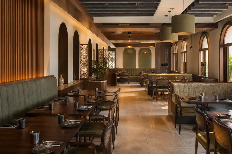 Indian restaurant with suspended baffles, timber absorption and upholstered seating.