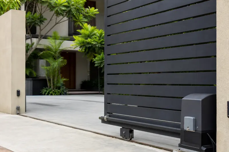 Sliding driveway gate shows its drive motor and safety sensing at an Indian residence.