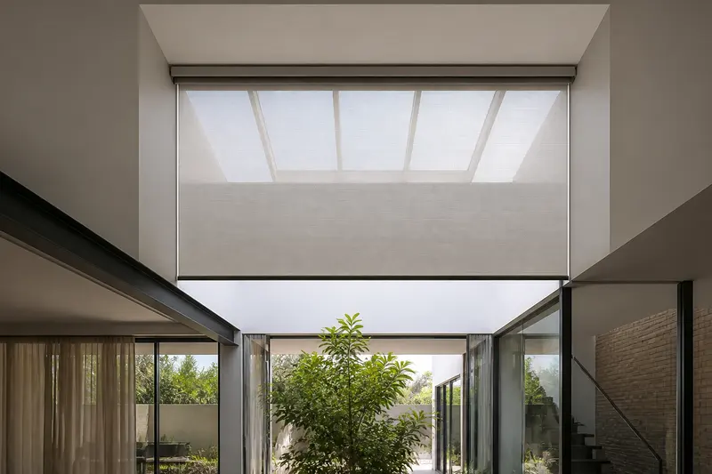 Motorized skylight shade controls overhead glare in a double-height interior.