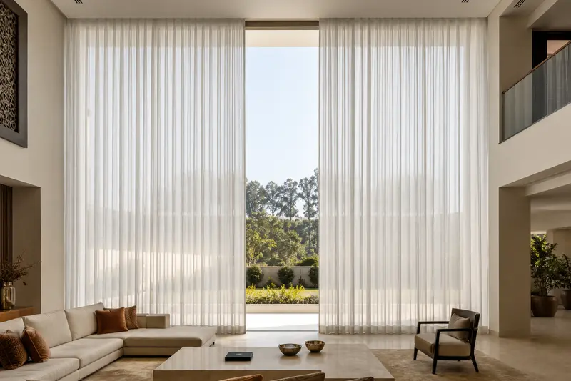 Continuous motorized curtains cover a tall double-height glazed wall.