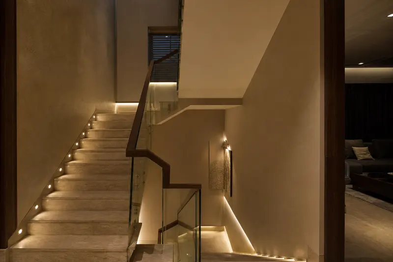 Staircase combines low-level safe-path lighting with soft architectural illumination.