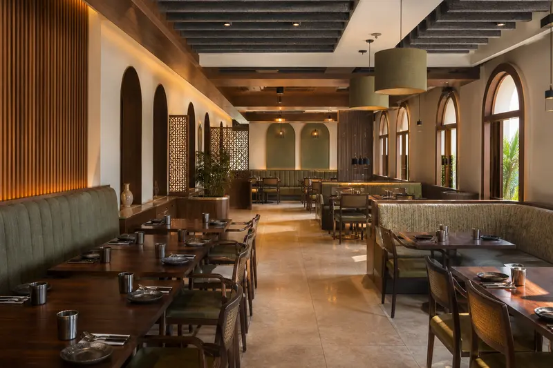Indian restaurant with suspended baffles, timber absorption and upholstered seating.