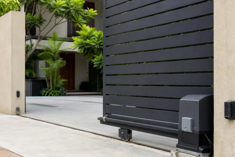Sliding driveway gate shows its drive motor and safety sensing at an Indian residence.