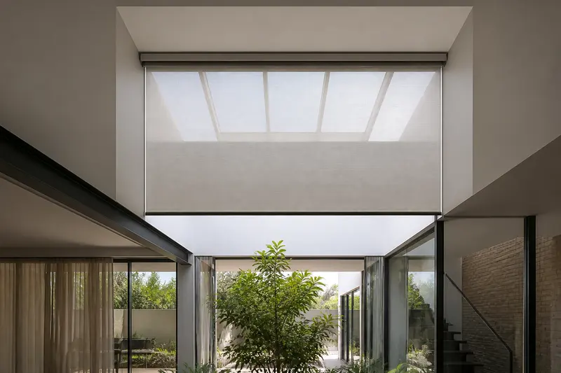 Motorized skylight shade controls overhead glare in a double-height interior.