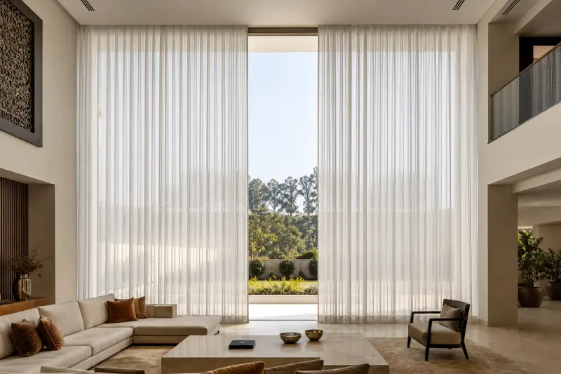 Continuous motorized curtains cover a tall double-height glazed wall.