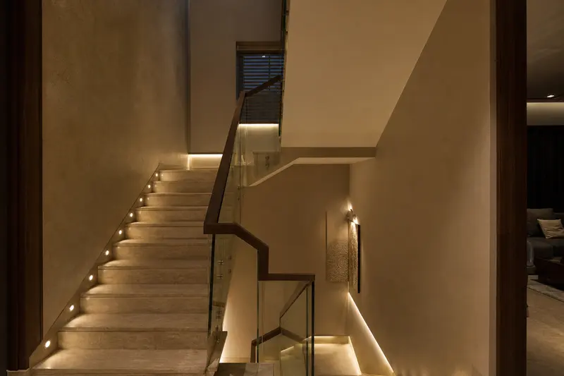 Staircase combines low-level safe-path lighting with soft architectural illumination.