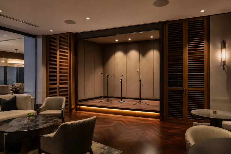 Hotel lounge performance alcove with microphones, ceiling audio and acoustic finishes.