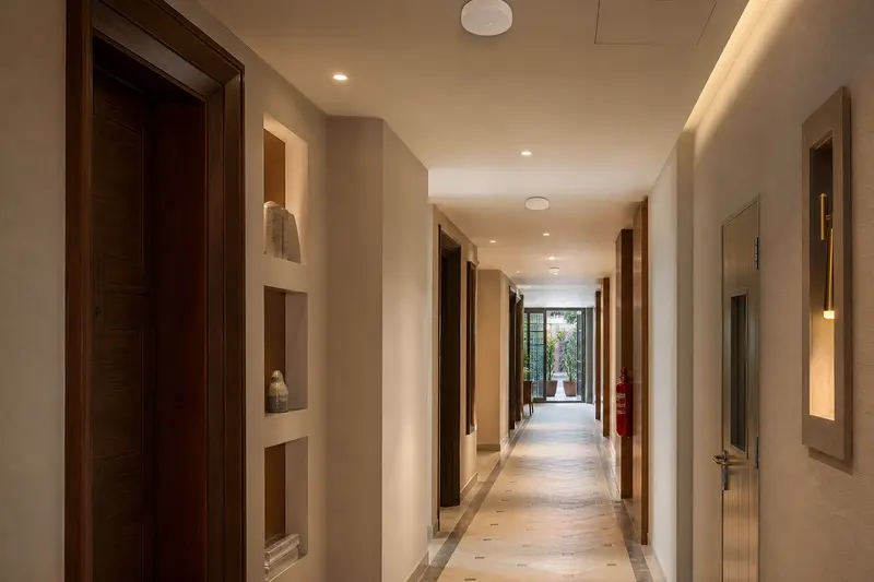 Long hotel corridor with multiple restrained ceiling access points and varied wall geometry.
